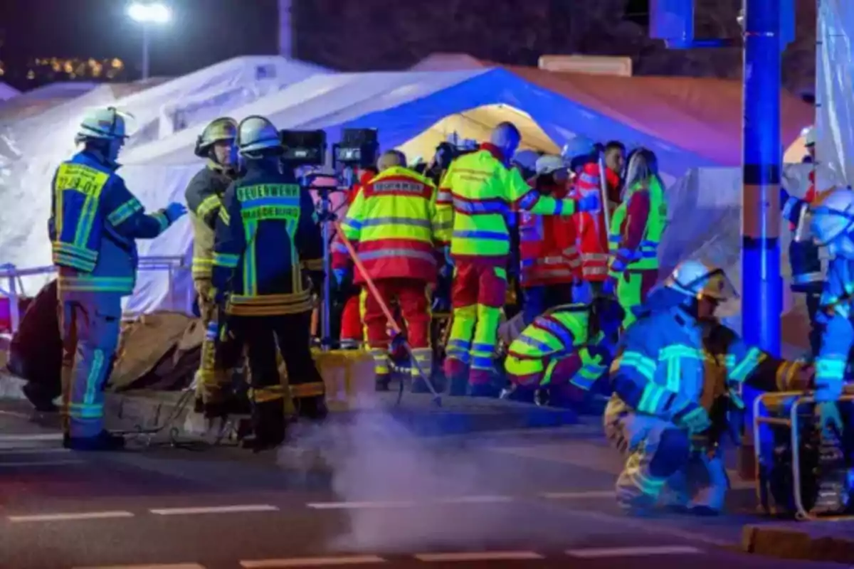 Un grupo de bomberos y personal de emergencia trabajando en una escena iluminada por luces brillantes.