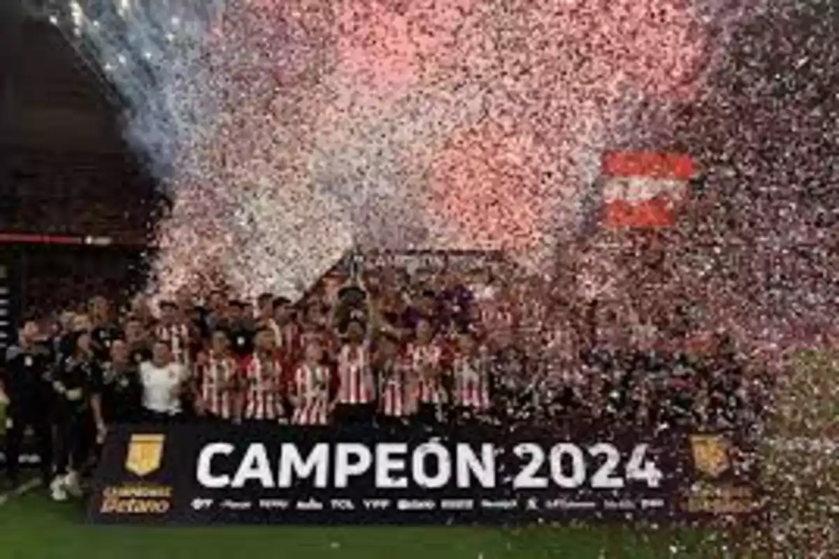 Un equipo de fútbol celebra su victoria como campeones de 2024 rodeados de confeti y fuegos artificiales.