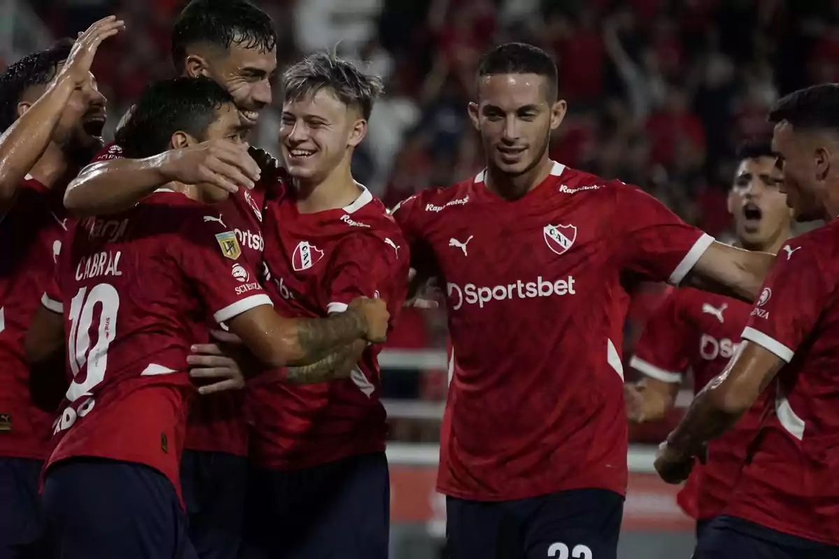 Jugadores de fútbol con camisetas rojas celebrando en el campo.