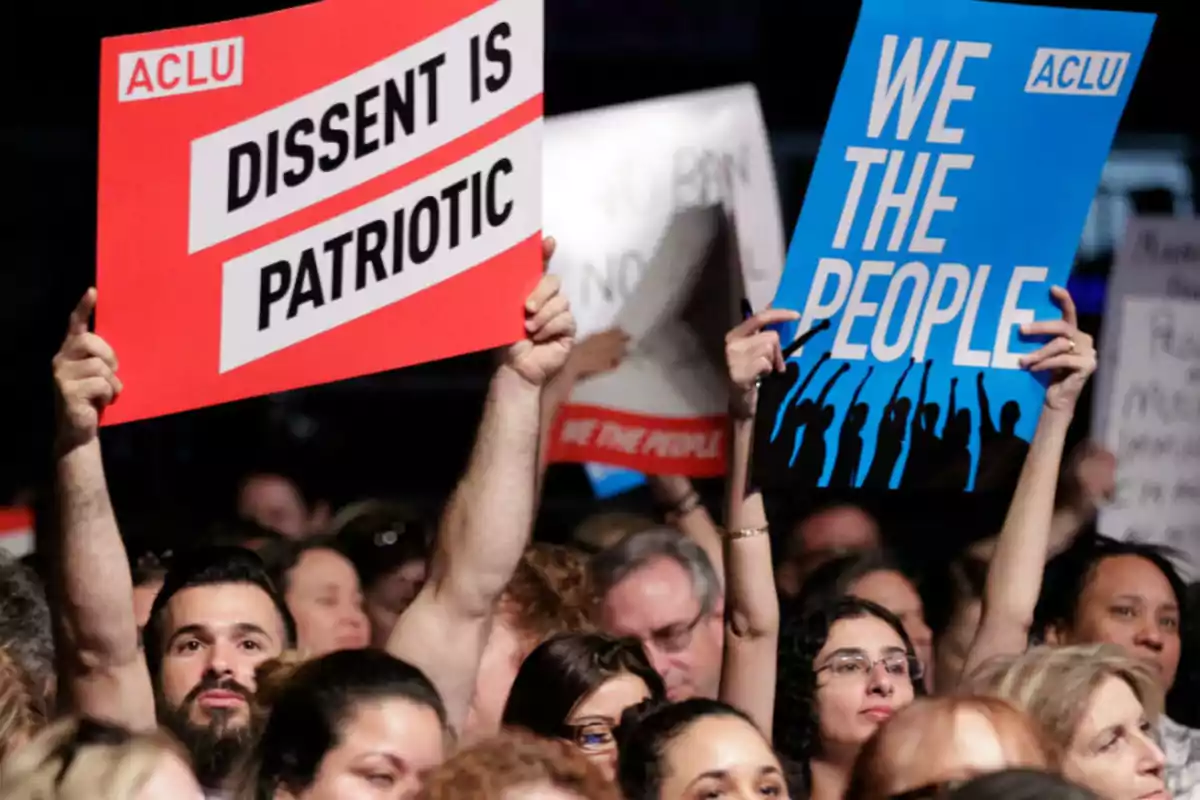 Personas en una multitud sosteniendo carteles de la ACLU que dicen 