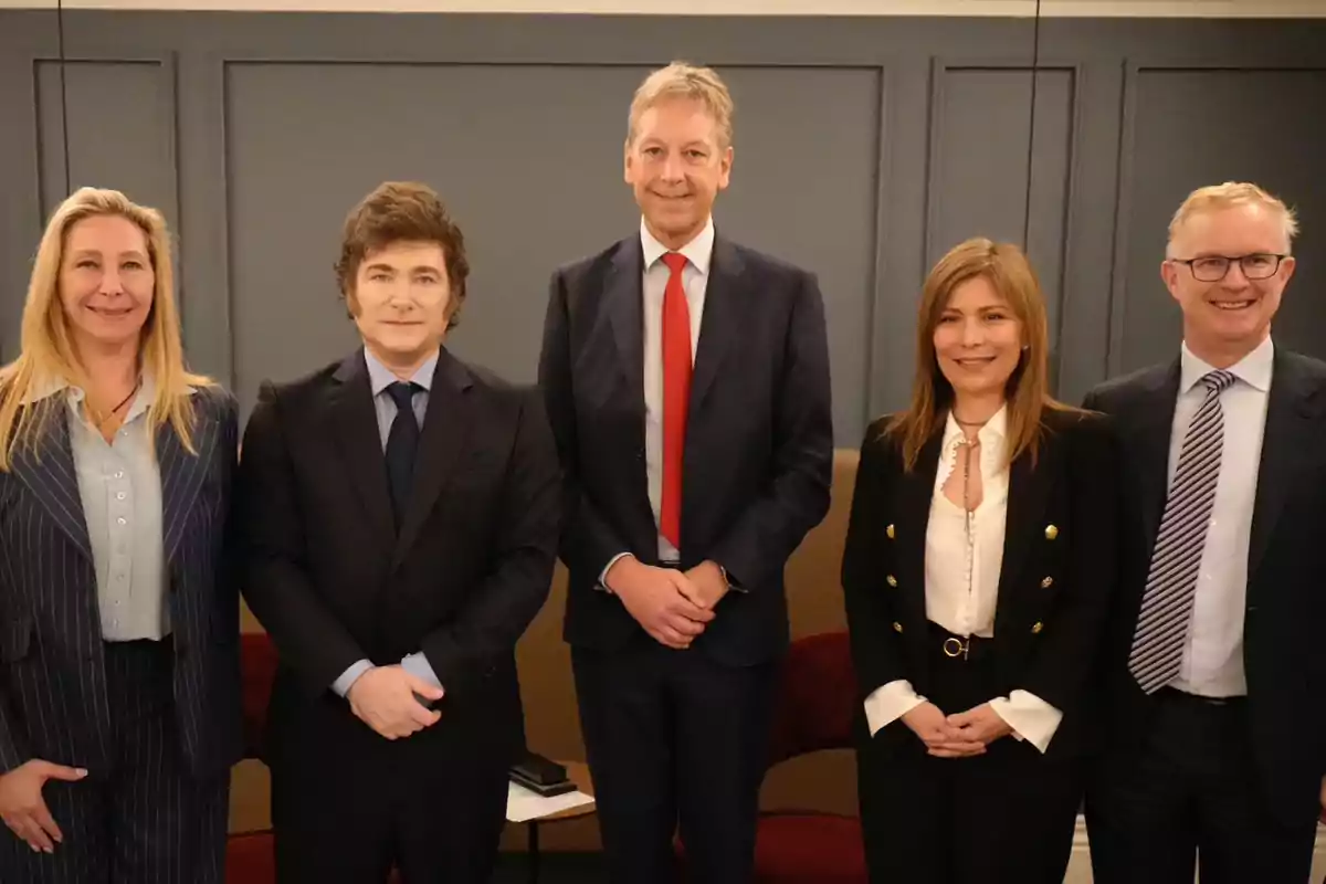 Cinco personas vestidas de manera formal posan para una foto en un ambiente interior.