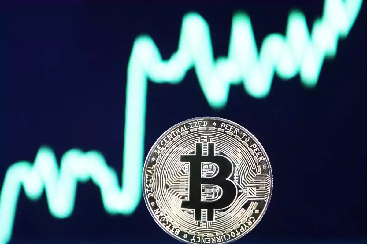 Moneda de Bitcoin frente a un gráfico de líneas en movimiento.