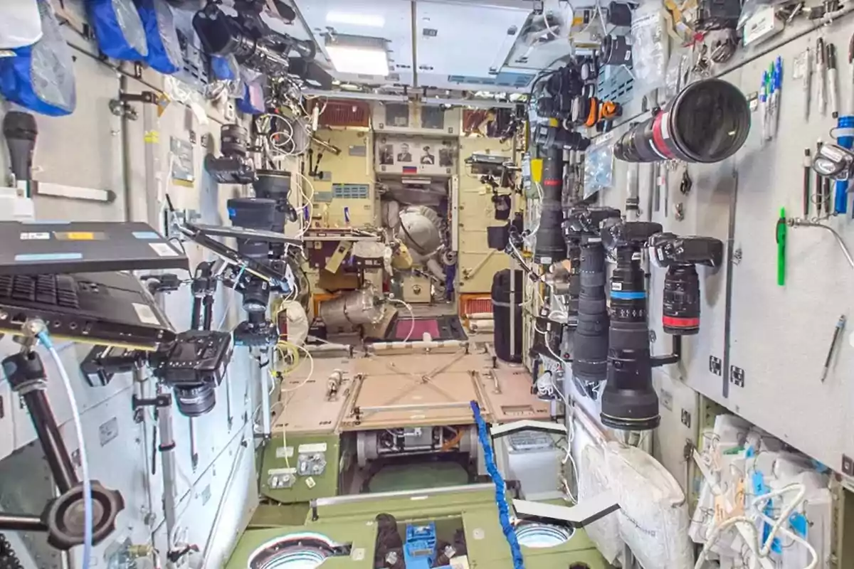 Interior de una estación espacial con cámaras y equipos tecnológicos montados en las paredes.