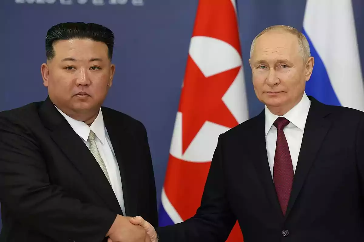 Dos hombres de traje estrechándose la mano frente a las banderas de Corea del Norte y Rusia.