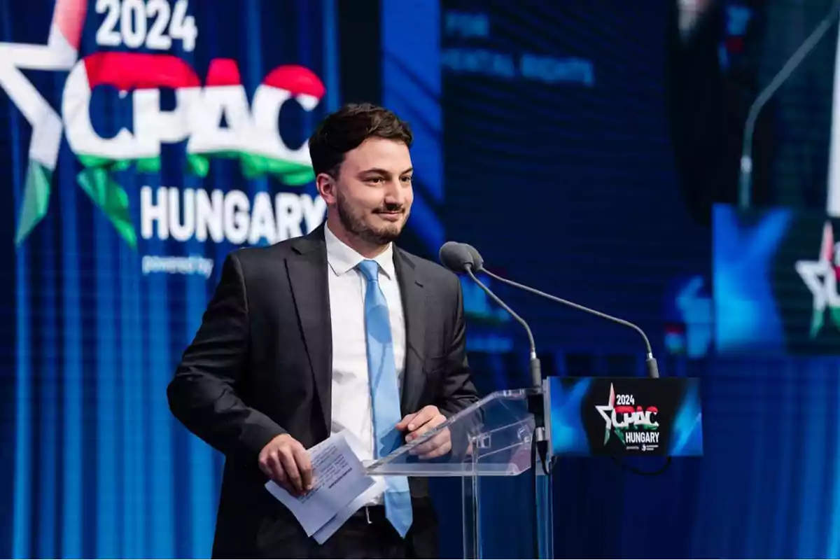 Un hombre de traje y corbata azul está hablando en un podio durante el evento CPAC 2024 en Hungría.