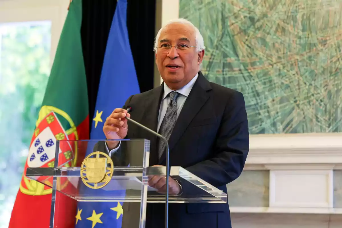 Un hombre de traje hablando en un podio con las banderas de Portugal y la Unión Europea detrás.