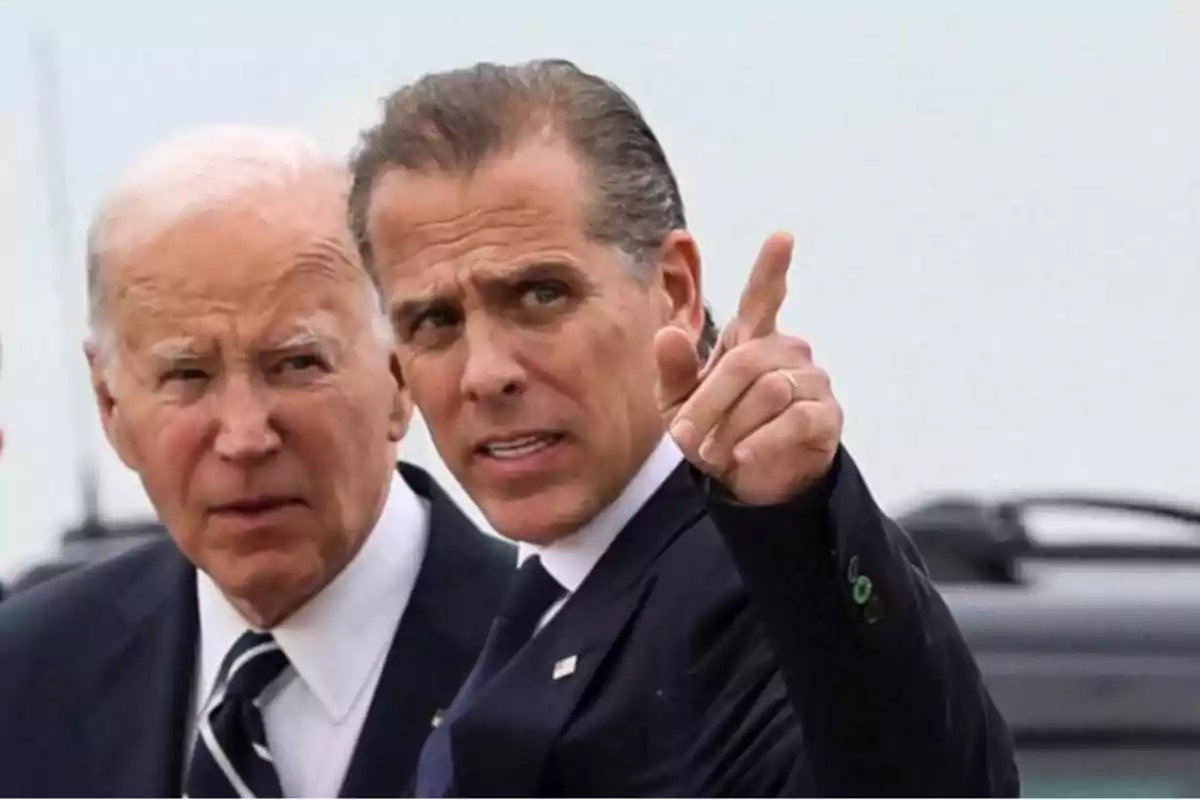 Dos hombres de traje, uno de ellos señalando hacia adelante.