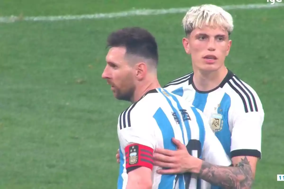 Dos jugadores de fútbol con uniforme de Argentina en el campo de juego.