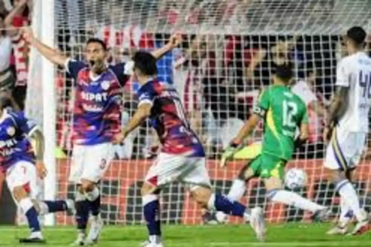 Jugadores de fútbol celebrando un gol frente a la portería durante un partido.