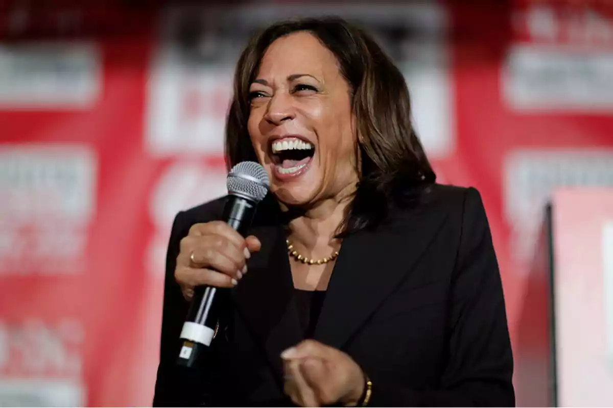 Persona sonriendo y hablando en un micrófono con un fondo rojo.