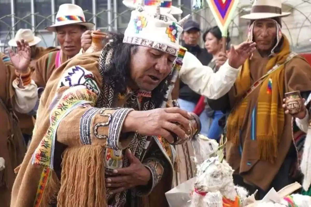 Un grupo de personas participa en una ceremonia tradicional andina, con vestimenta colorida y elementos rituales.