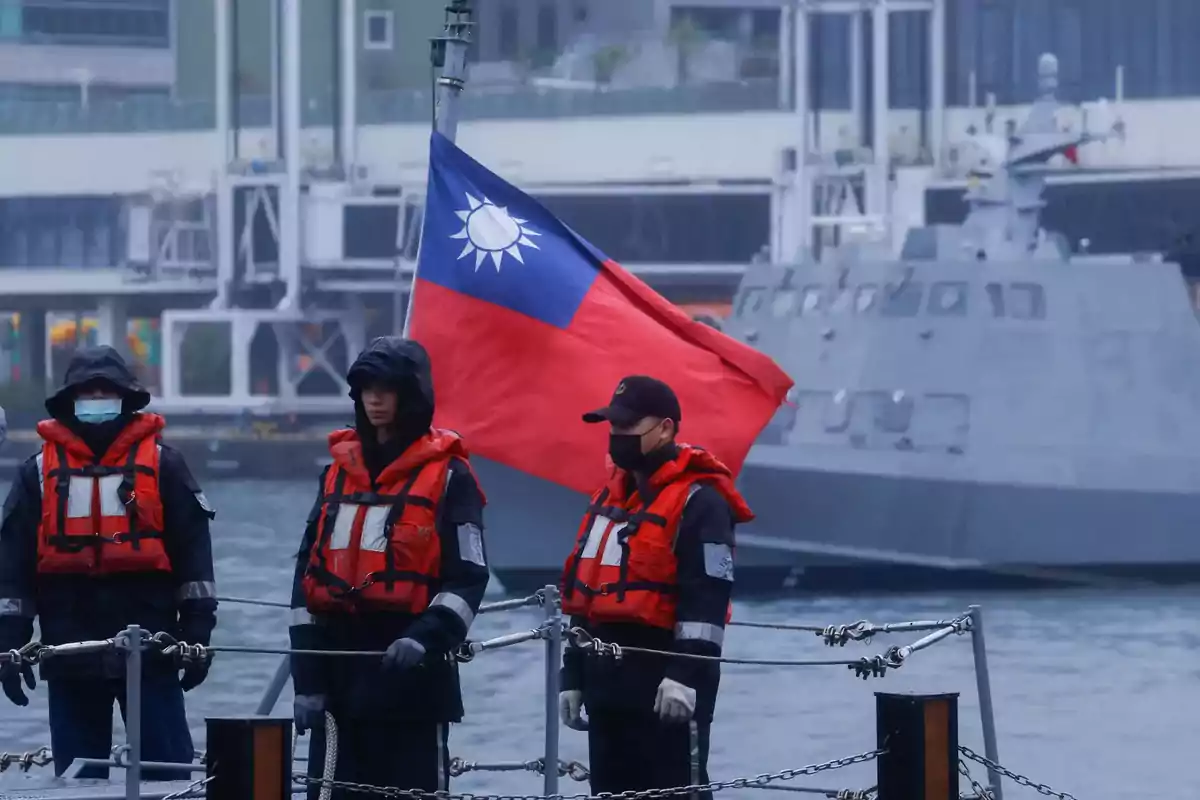 People with orange life jackets on a boat with a flag waving in the background.