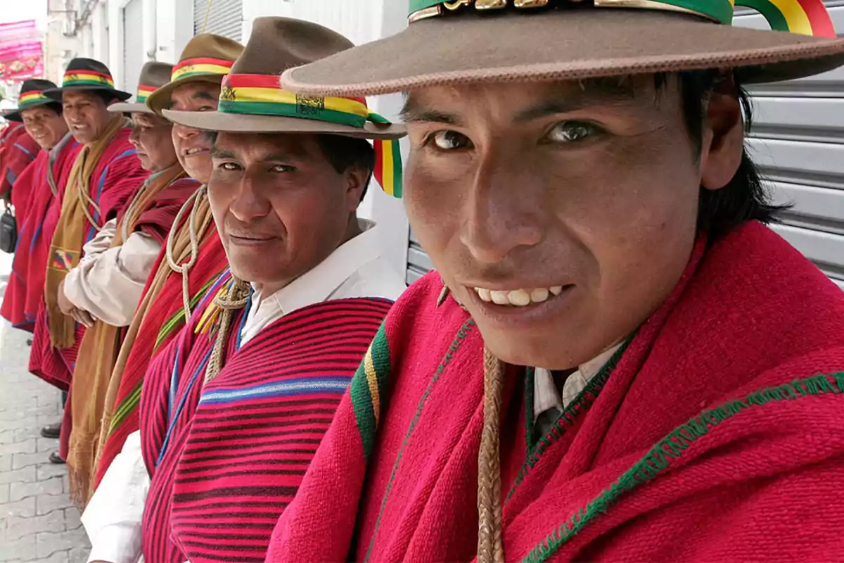 Un grupo de hombres con sombreros y ponchos coloridos, alineados y mirando a la cámara.