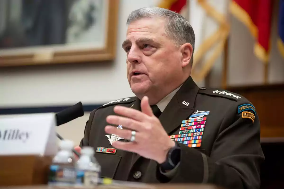 Un hombre en uniforme militar hablando en un entorno formal con medallas y distintivos visibles en su chaqueta.