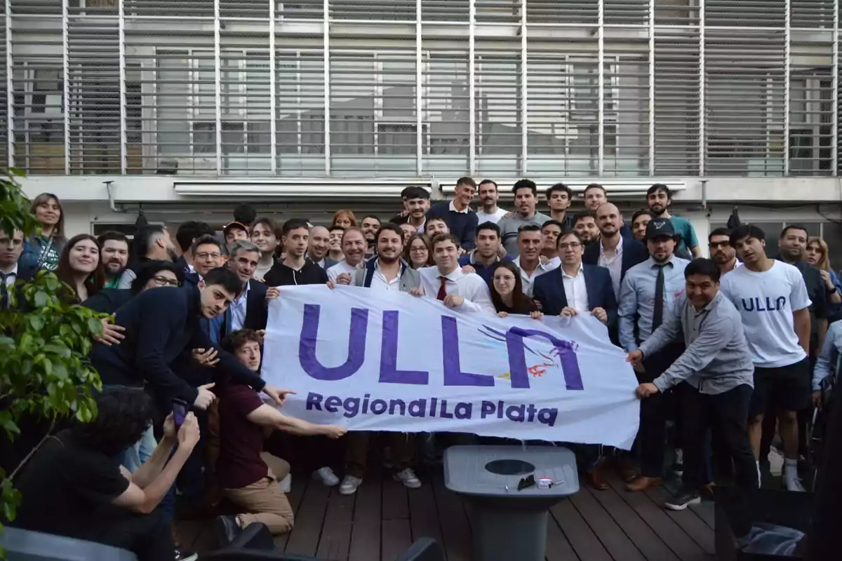 Un grupo de personas posando juntas mientras sostienen una pancarta que dice "ULLA Regional La Plata" en un espacio al aire libre.