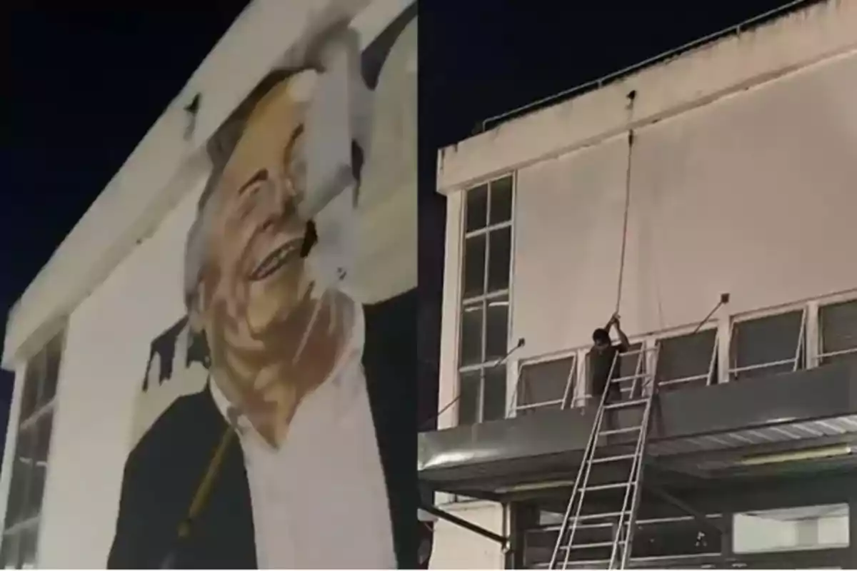 Una persona en una escalera retira un cartel de un edificio durante la noche.