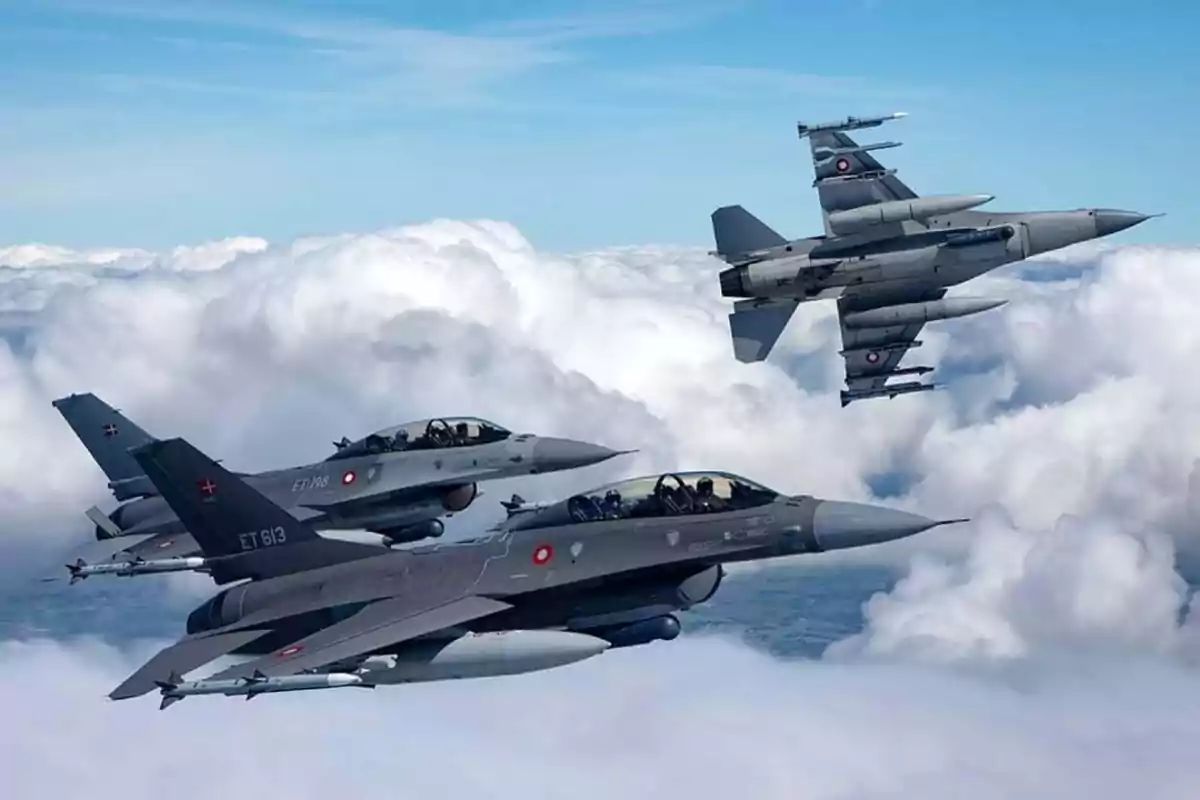 Tres aviones de combate volando sobre las nubes en formación.