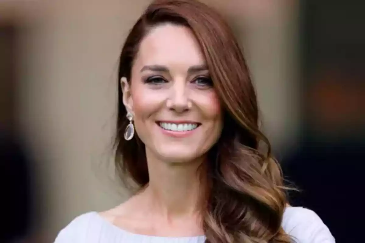 Una mujer sonriente con cabello castaño y aretes elegantes.