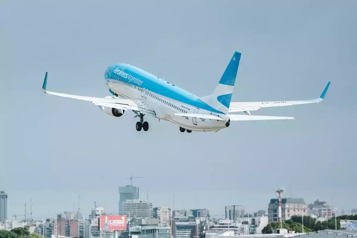 Un avión de Aerolíneas Argentinas despegando sobre una ciudad.