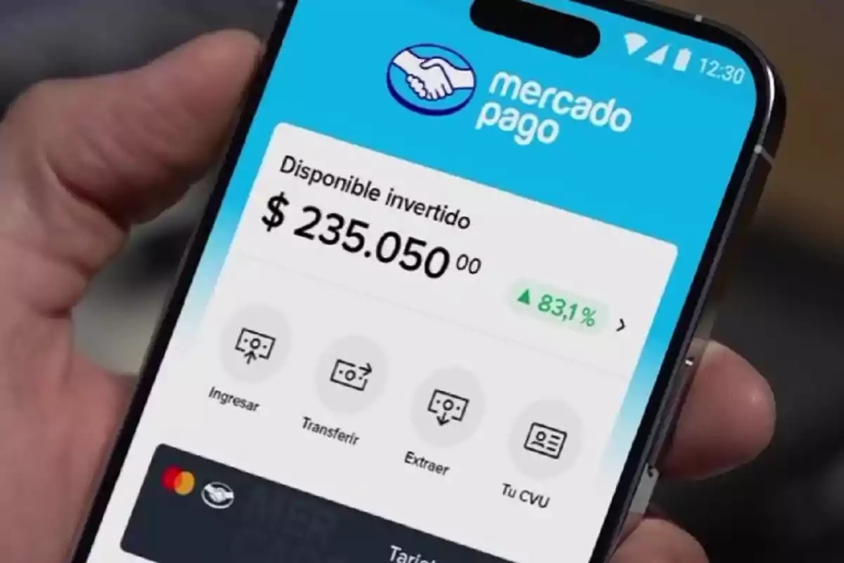 Persona sosteniendo un teléfono móvil que muestra la aplicación de Mercado Pago con un saldo disponible de 235,050 y un incremento del 83.1%