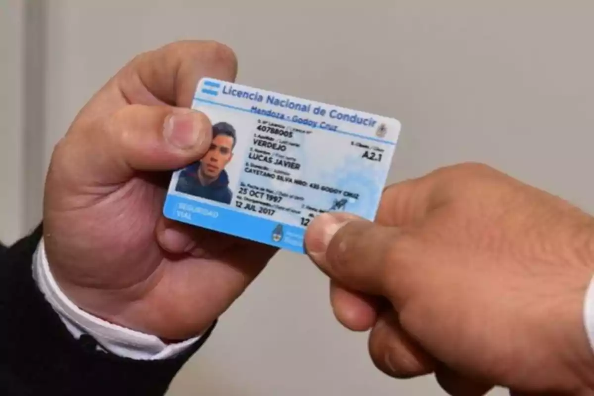 Una persona entregando una licencia de conducir argentina a otra persona.