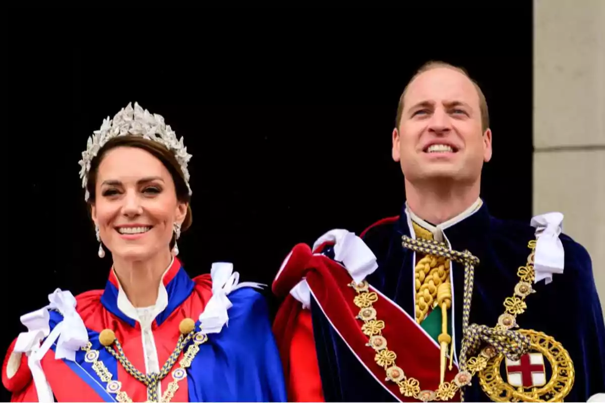 Una pareja vestida con trajes formales y adornos ceremoniales sonríe mientras está de pie juntos.