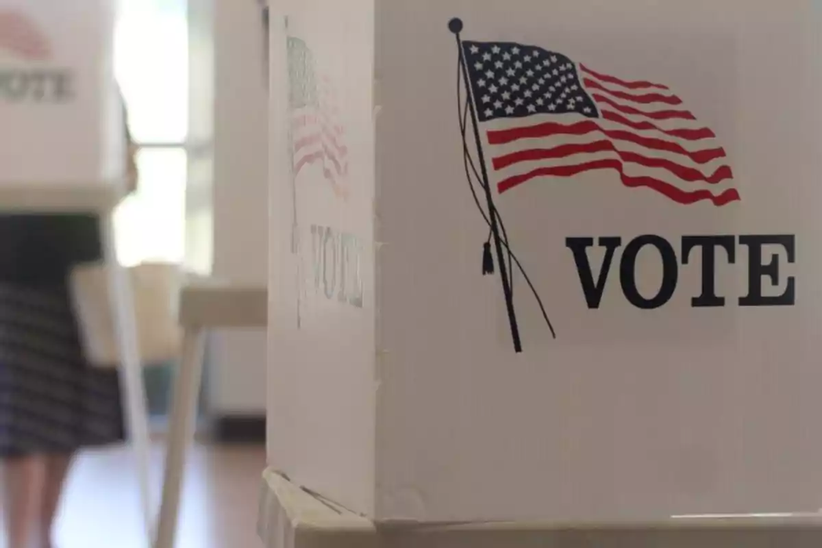 Urna de votación con la bandera de Estados Unidos y la palabra "VOTE" en un centro de votación.