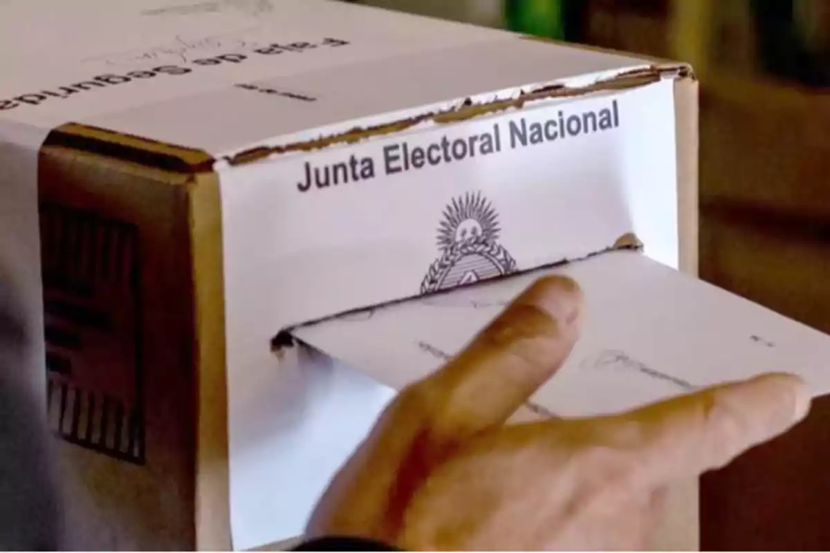 Una persona introduce un sobre en una urna de votación de la Junta Electoral Nacional.