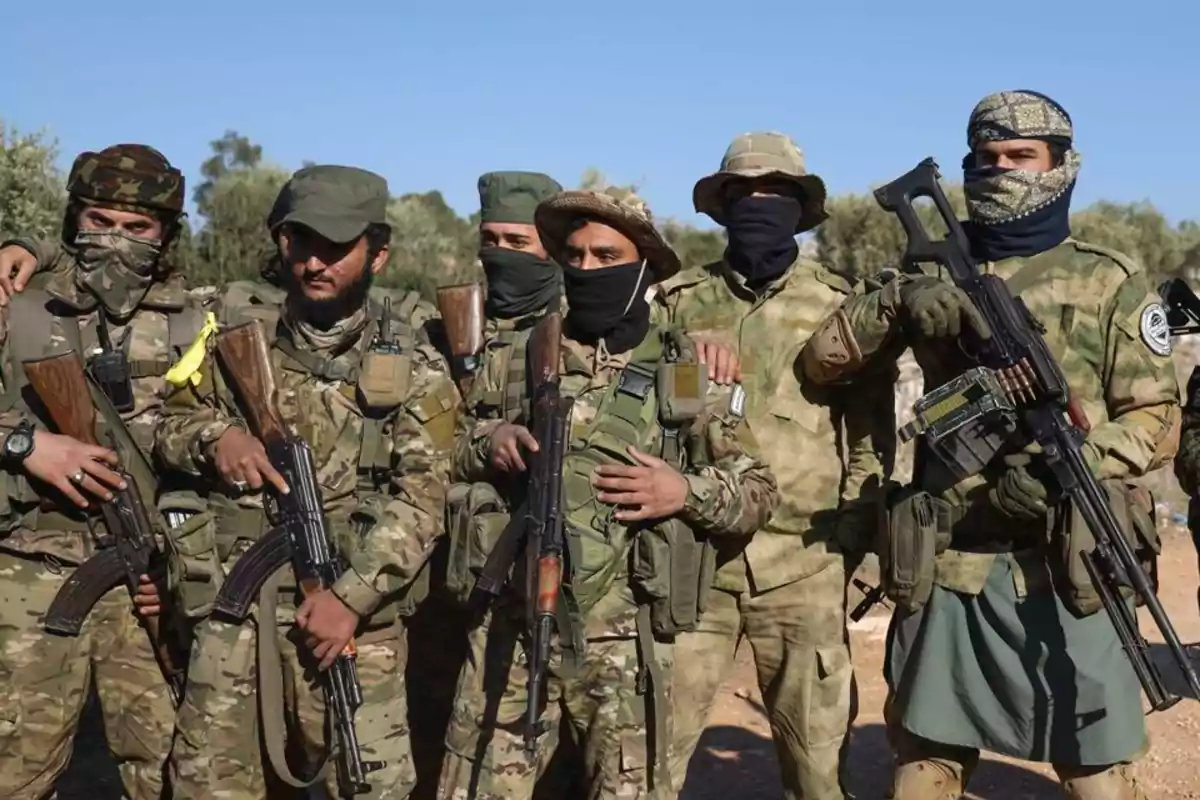 Un grupo de personas vestidas con uniformes militares y armadas posando al aire libre.