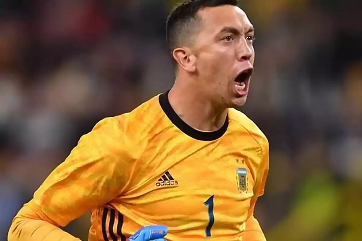 Un jugador de fútbol con uniforme amarillo grita con emoción durante un partido.