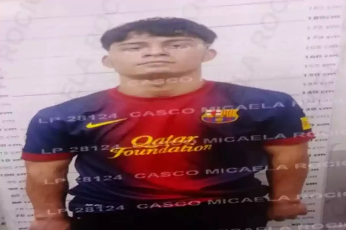 A man wearing an FC Barcelona soccer jersey posing in front of a height measurement wall.