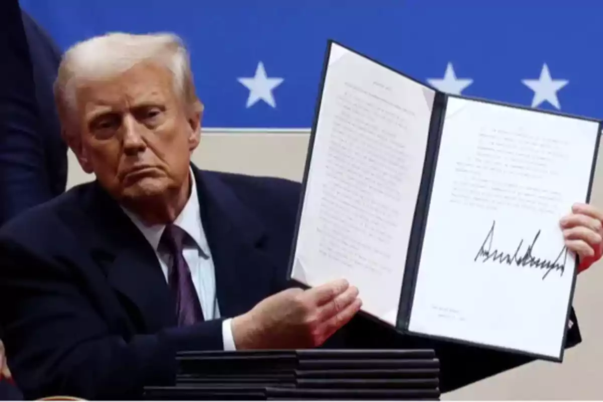 Un hombre de traje sostiene un documento abierto con una firma visible, con un fondo azul y estrellas blancas.