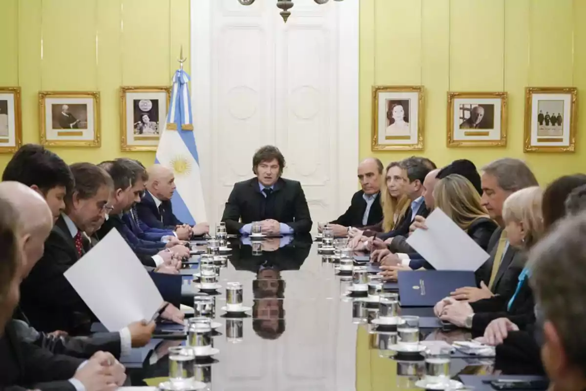 Una reunión de funcionarios en una sala con una bandera de Argentina y retratos en la pared.