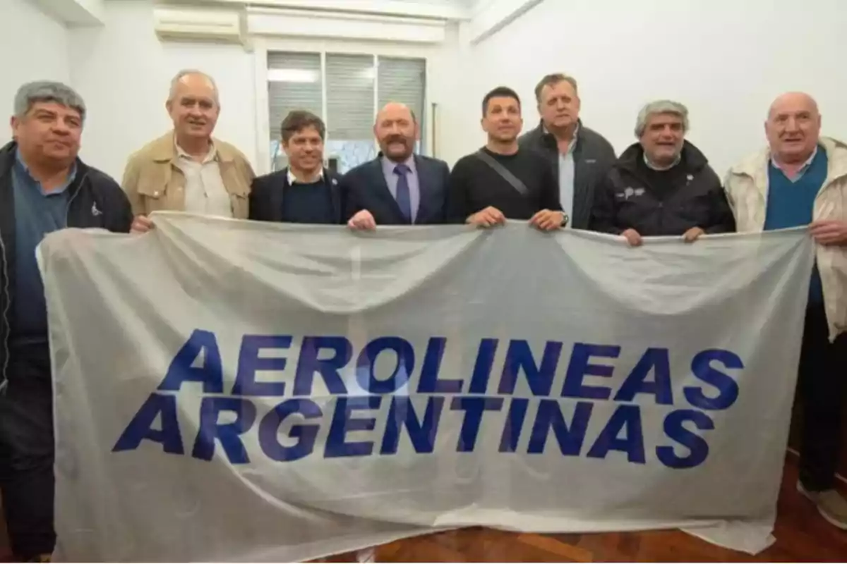 Un grupo de personas sostiene una bandera con el logo de Aerolíneas Argentinas en una sala.