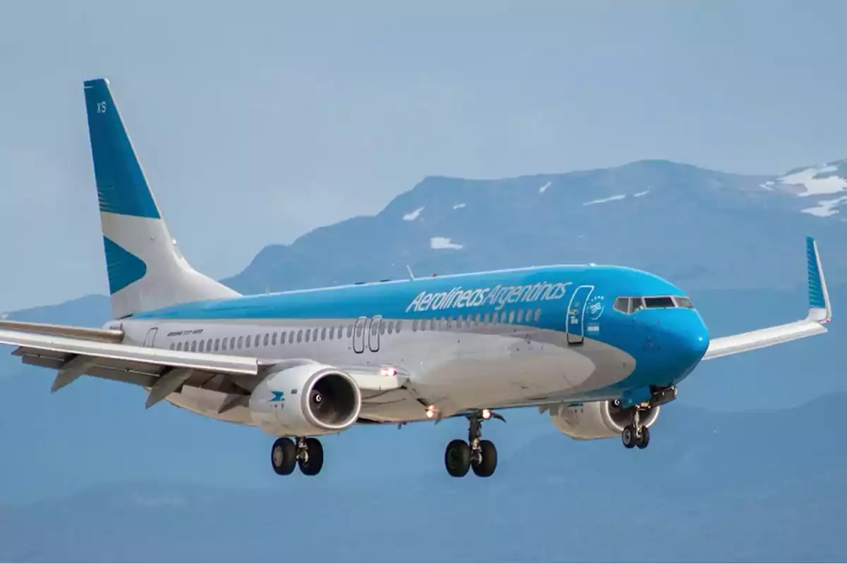 Avión de Aerolíneas Argentinas en vuelo con montañas de fondo