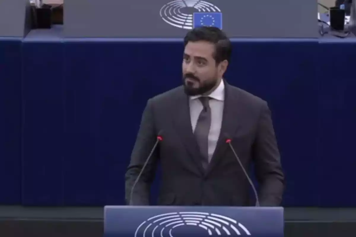 Un hombre de traje y corbata habla en un podio con el logotipo del Parlamento Europeo.