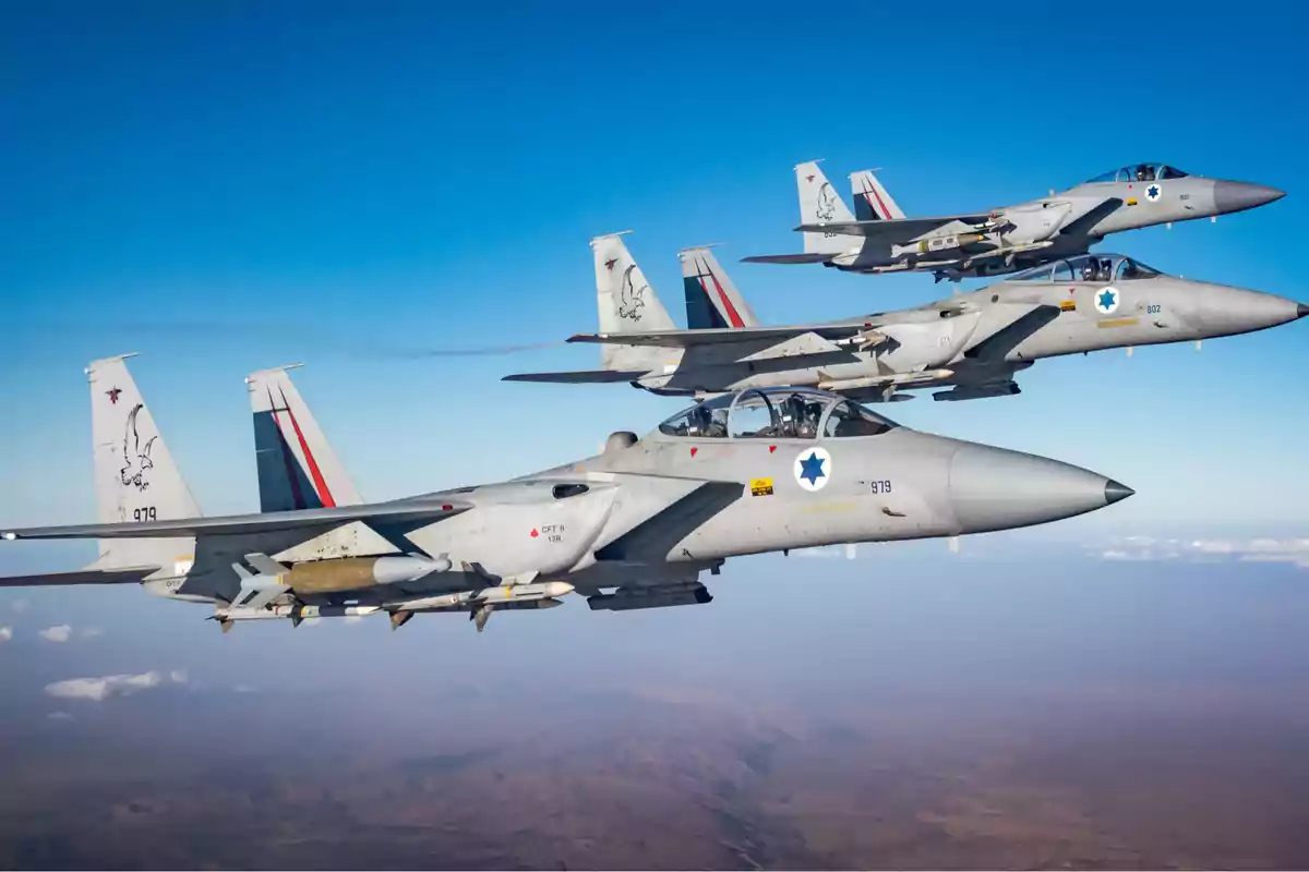 Tres aviones de combate volando en formación sobre un paisaje desértico bajo un cielo despejado.