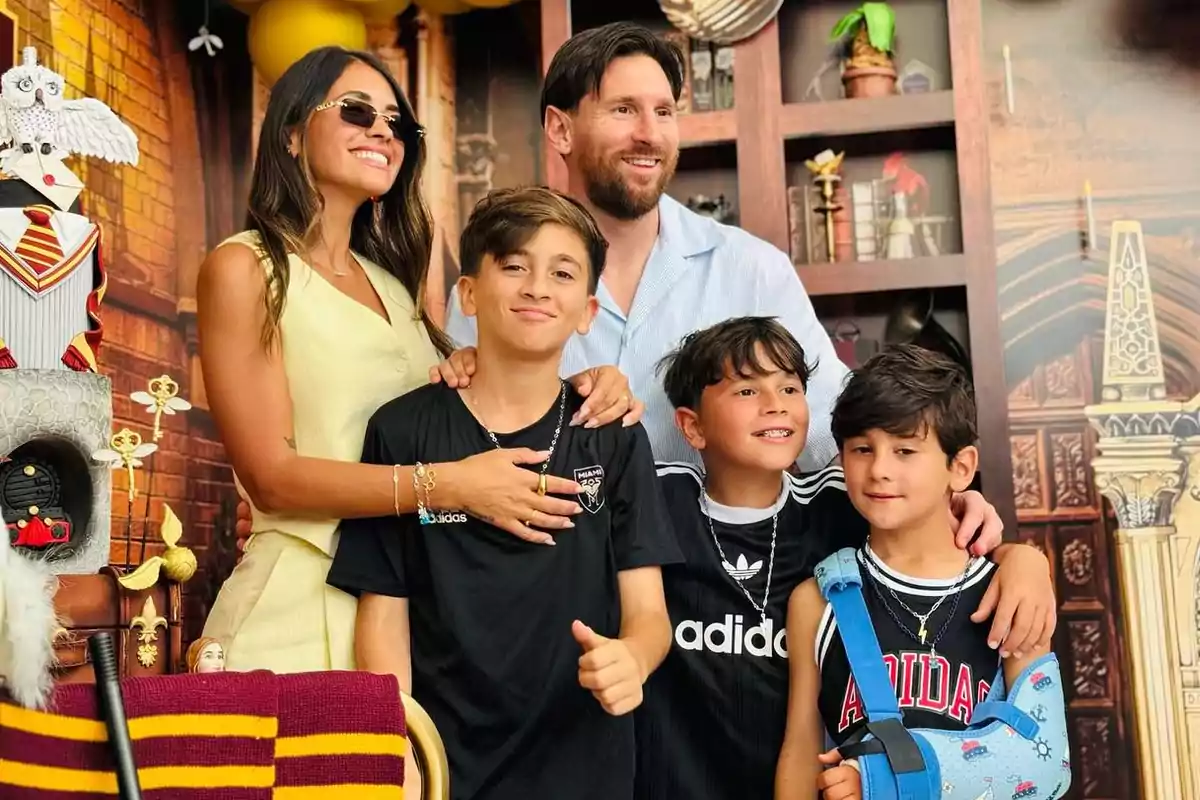 A smiling family poses in front of a themed decoration with a cake adorned with an owl figure and red and yellow details.