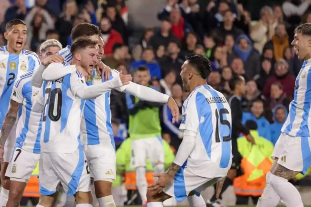 Jugadores de fútbol celebrando un gol en un partido con la camiseta de la selección argentina.