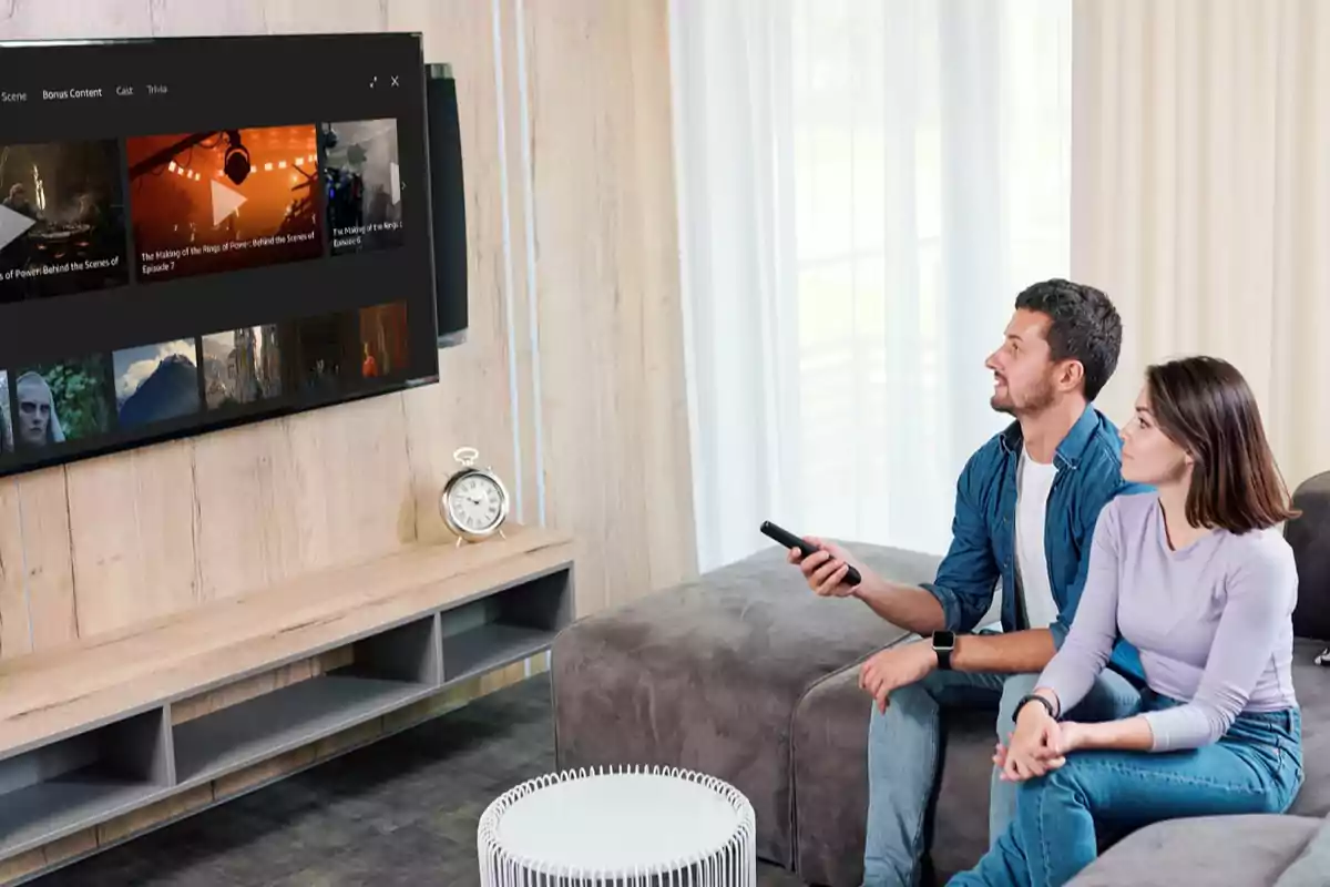 Una pareja sentada en un sofá observa la televisión en una sala de estar moderna.