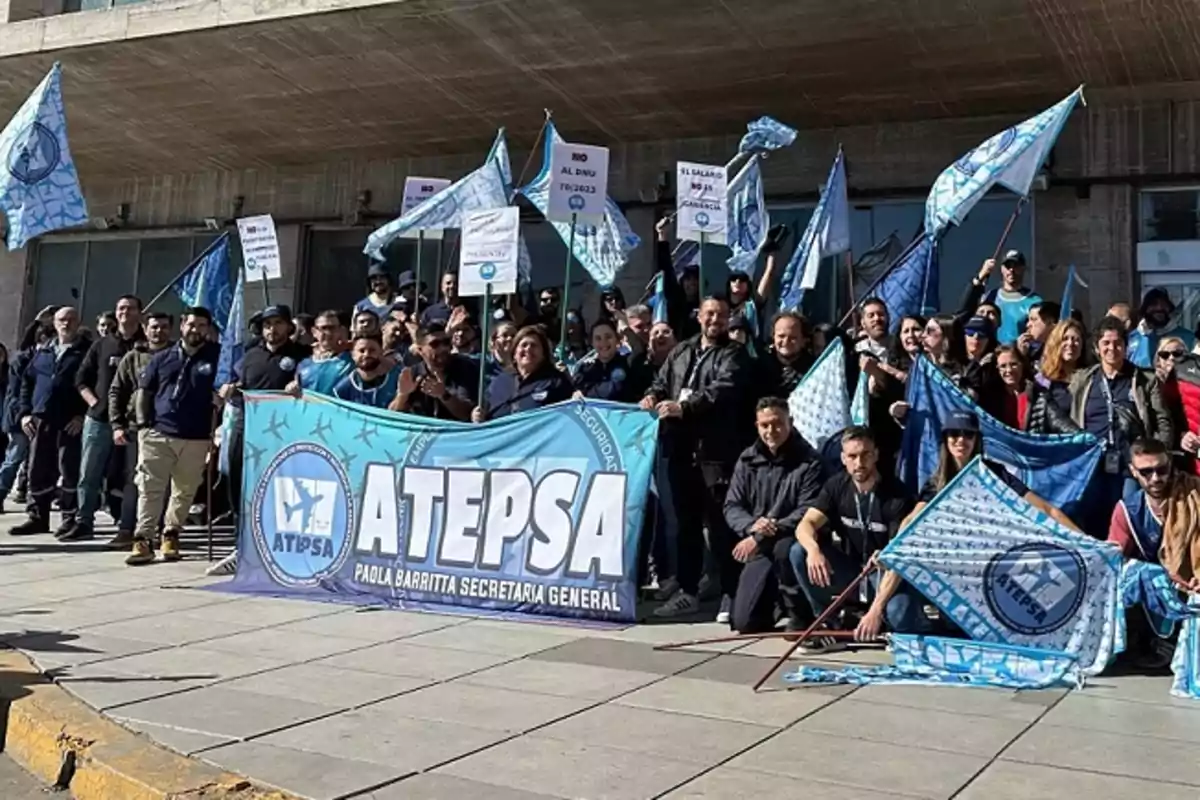 Un grupo de personas se manifiesta frente a un edificio sosteniendo banderas y pancartas de ATEPSA.