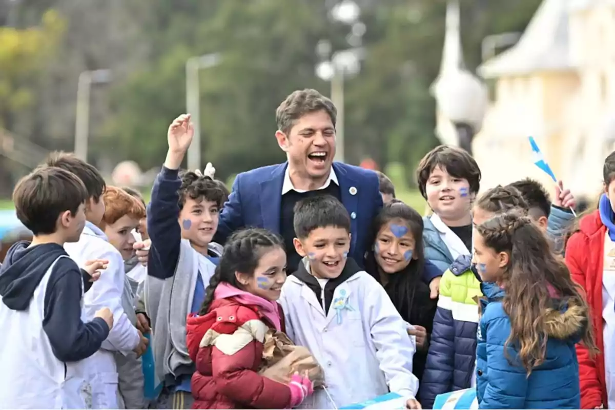 Un grupo de niños sonrientes rodea a un hombre que también está sonriendo en un ambiente al aire libre.