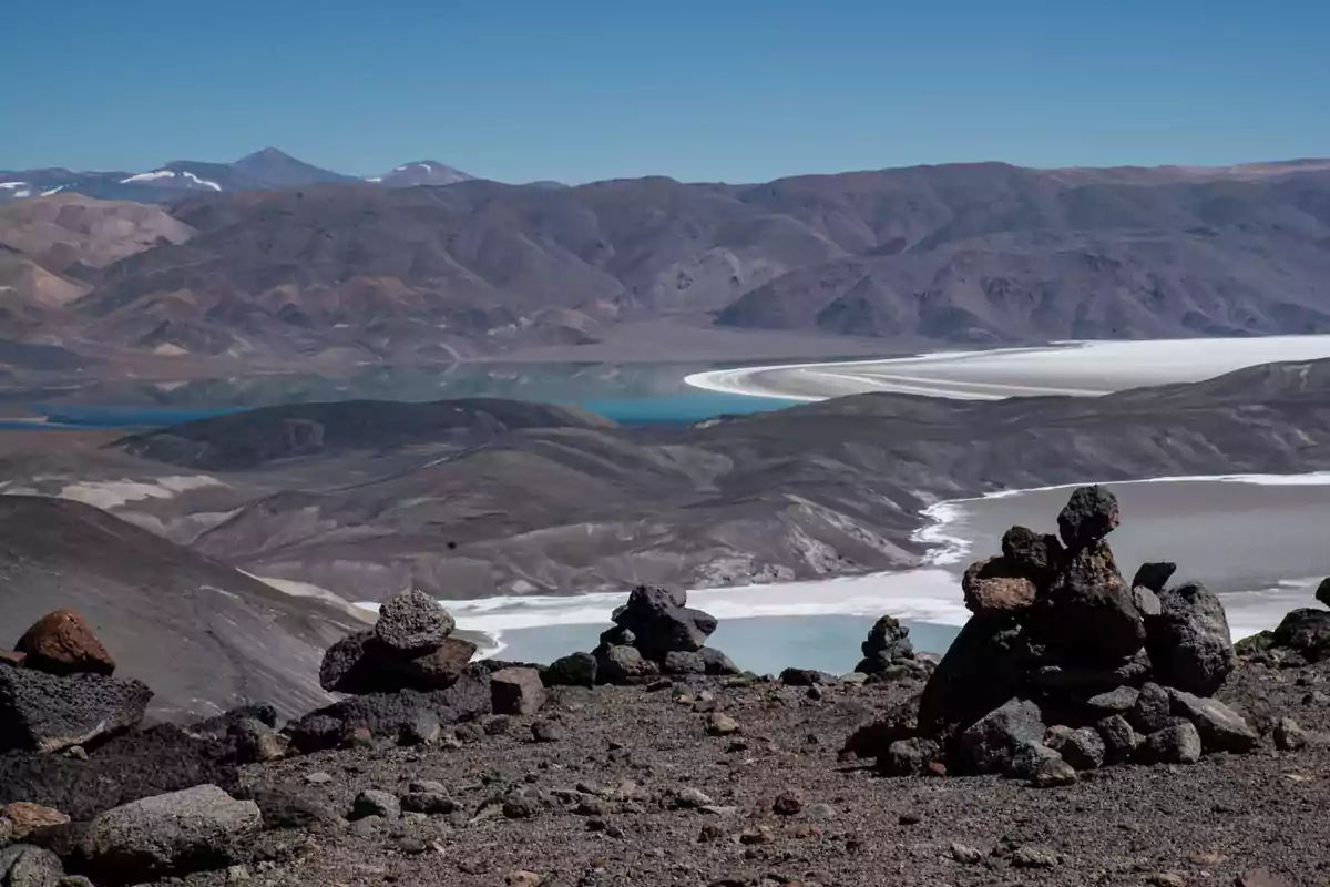 Paisaje montañoso con formaciones rocosas y lagunas de colores en el fondo.