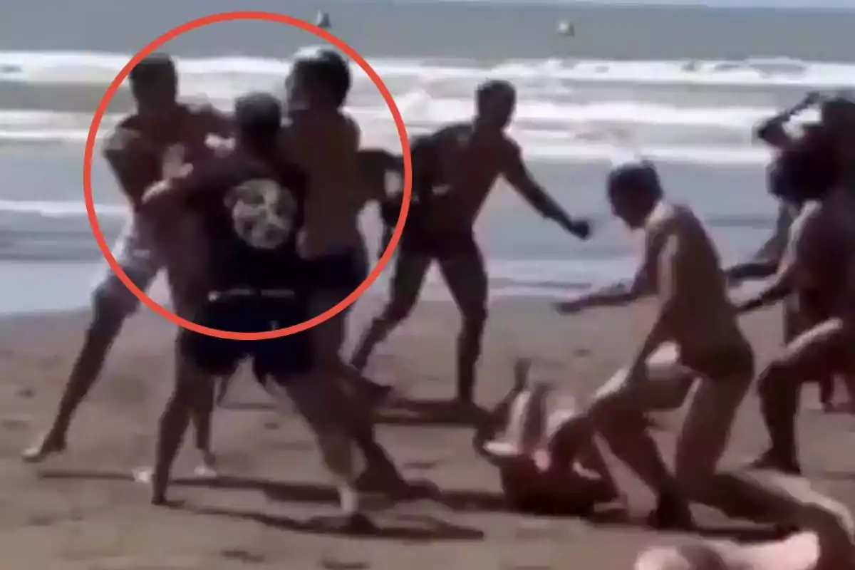 A group of people on the beach appears to be involved in a physical confrontation.