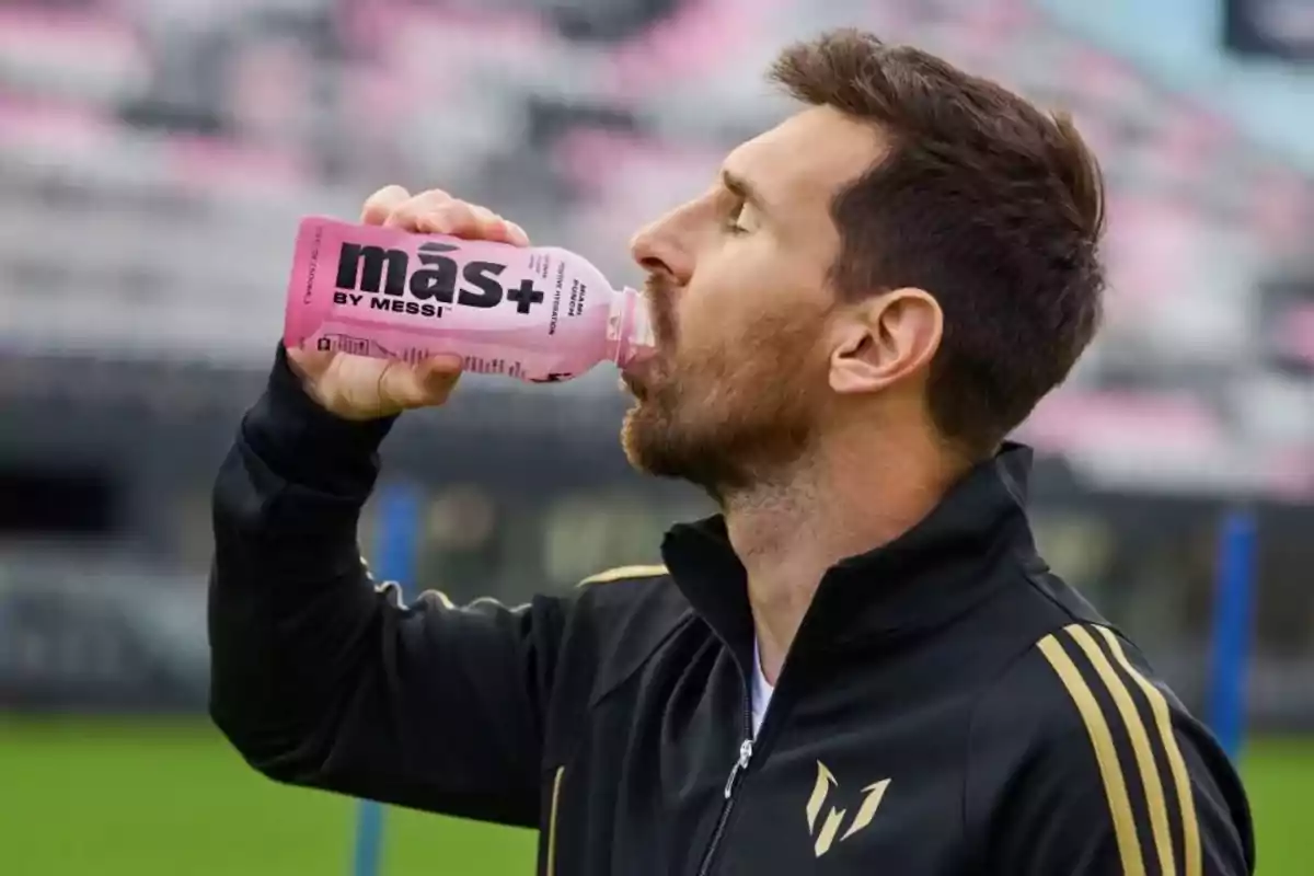 A man drinking from a pink bottle on a soccer field.