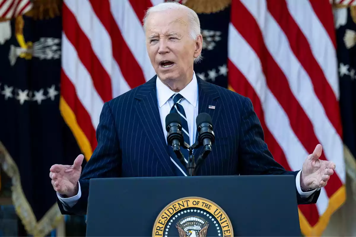 Un hombre de traje oscuro habla frente a un podio con el sello presidencial de Estados Unidos y banderas estadounidenses de fondo.