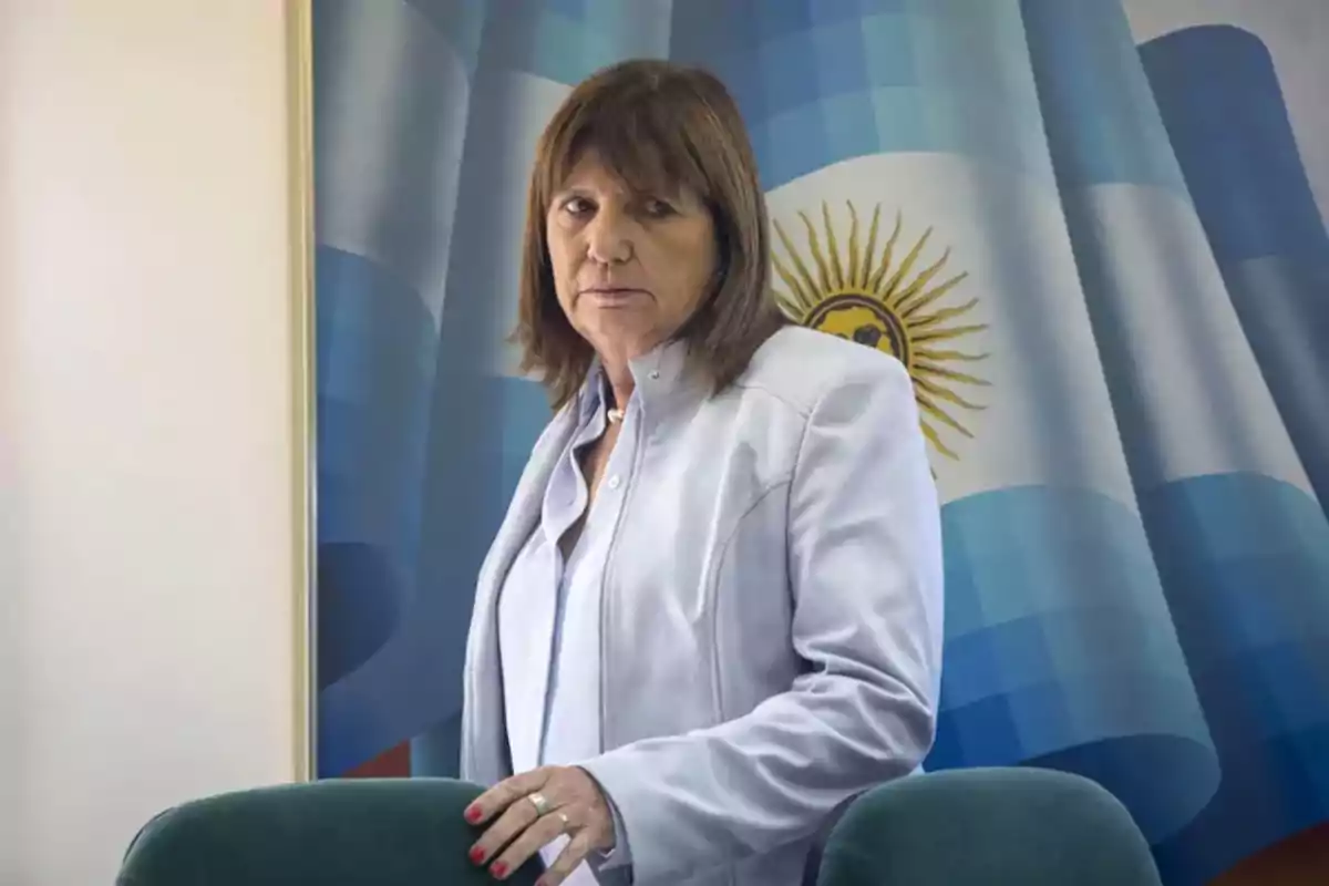 Mujer de pie frente a una bandera argentina.