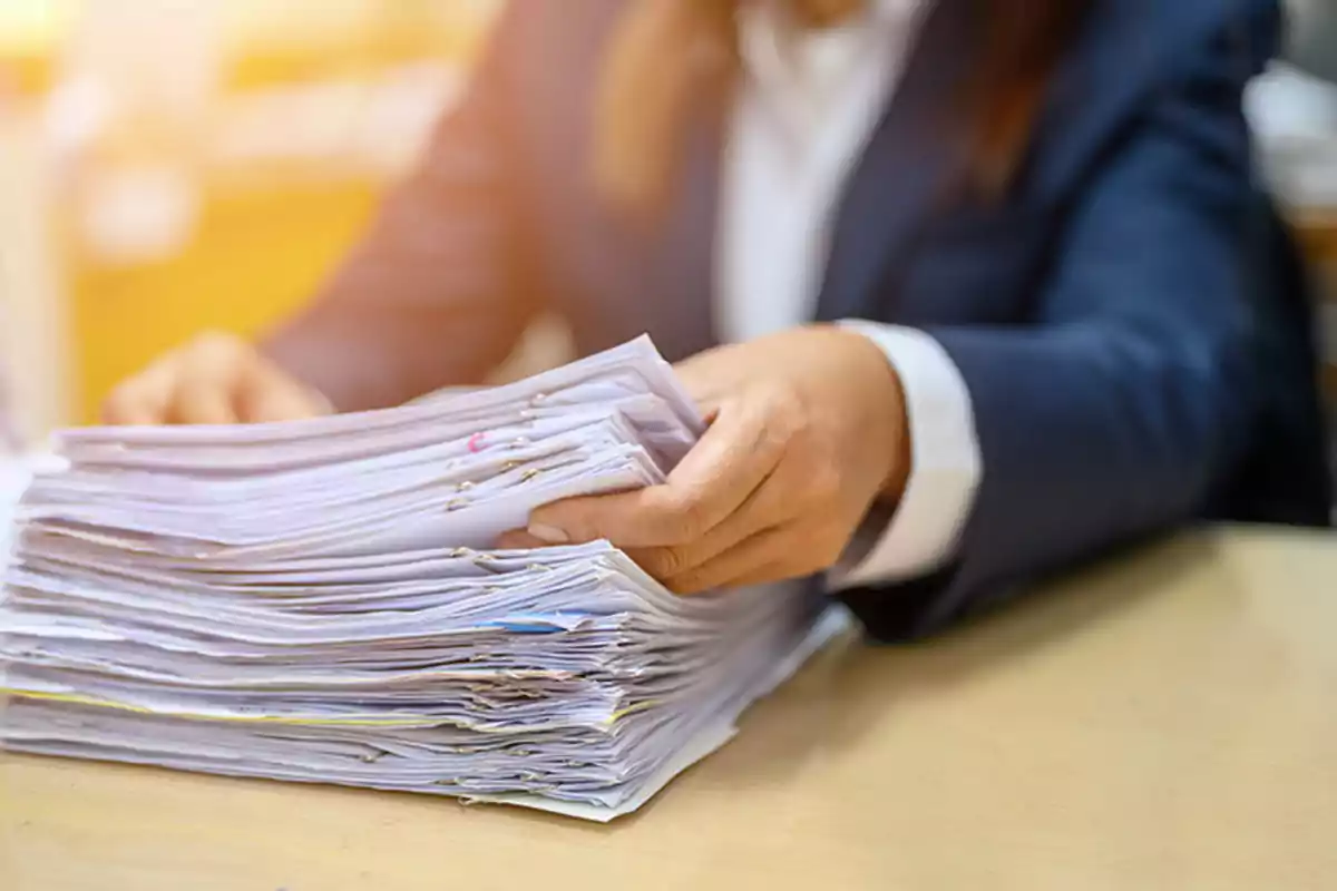 Persona revisando una pila de documentos en una oficina.