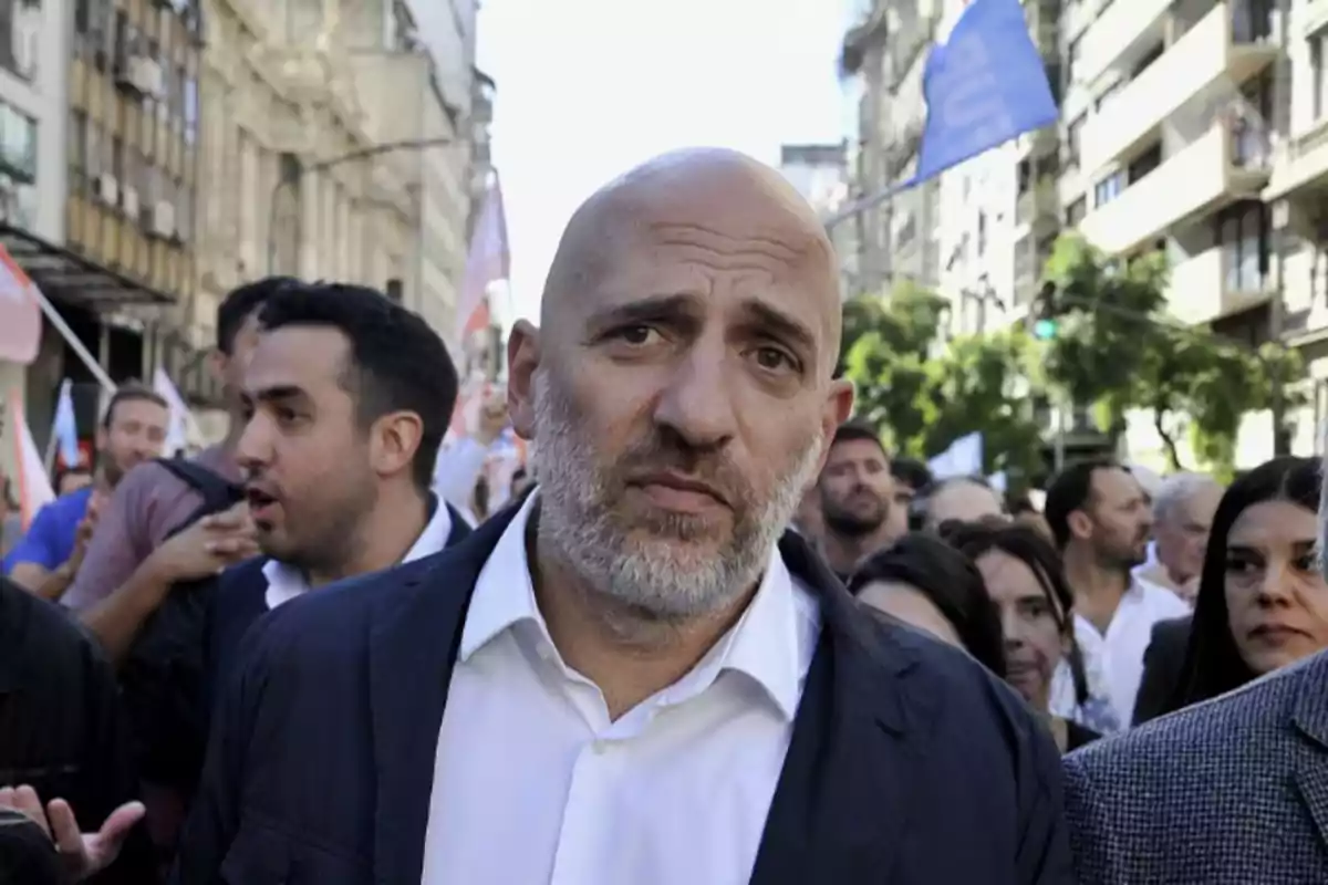 Un hombre calvo con barba en una manifestación en una calle concurrida.