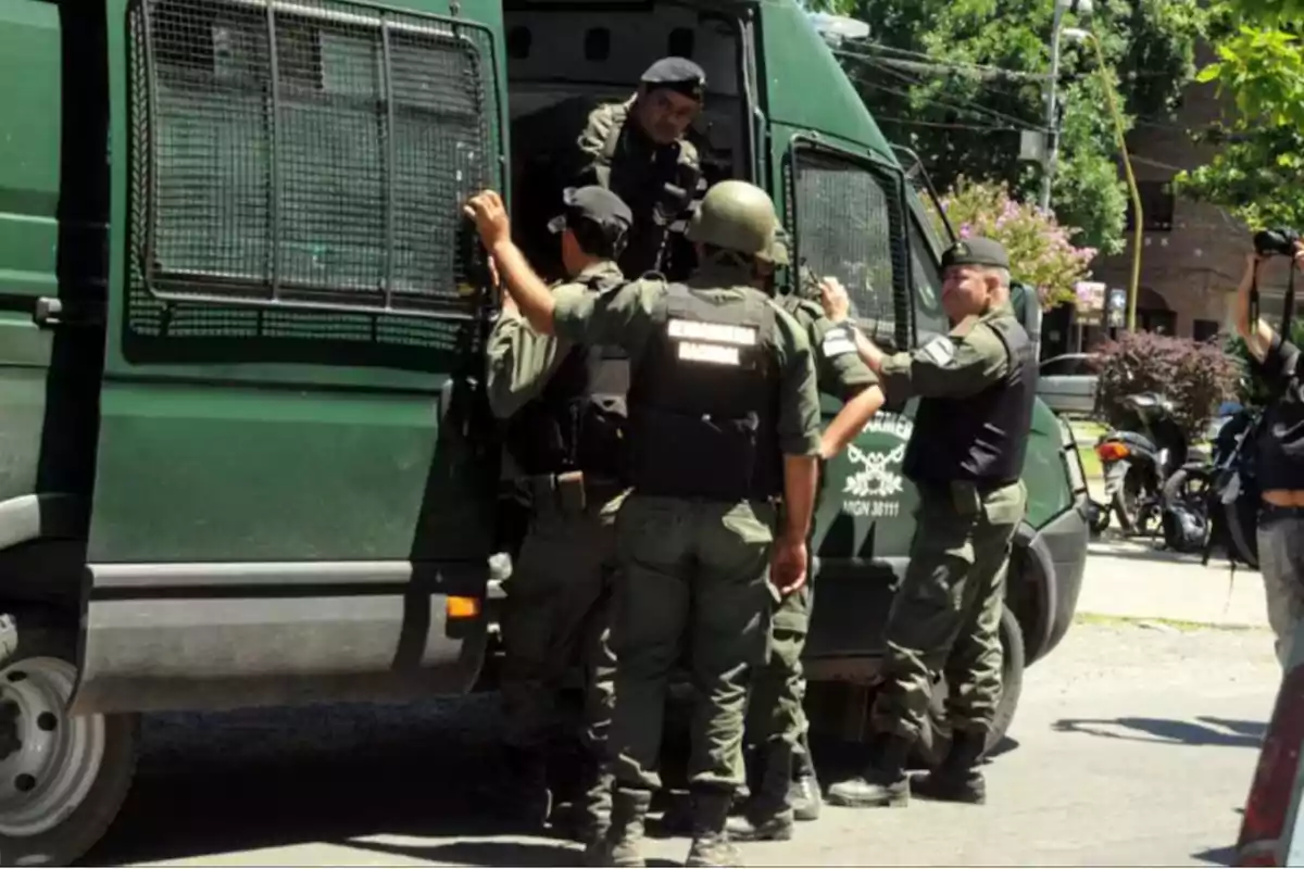 Un grupo de agentes de seguridad se encuentra alrededor de un vehículo verde en una calle.